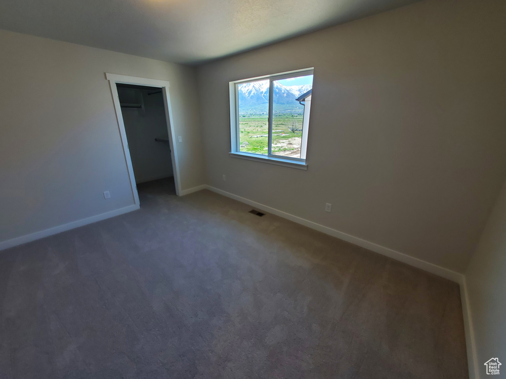 Unfurnished bedroom with baseboards, dark carpet, a closet, and a spacious closet