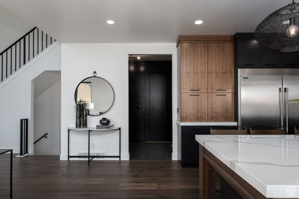 Kitchen with stainless steel built in fridge, dark wood-type flooring, recessed lighting, baseboards, and light stone counters