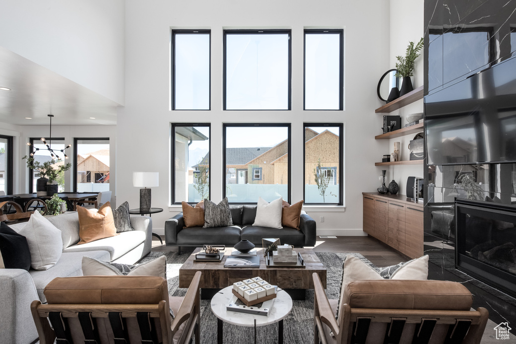 Living area featuring wood finished floors, a high ceiling, baseboards, and a chandelier