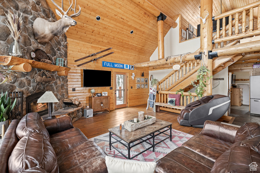 Living area with high vaulted ceiling, log walls, wood-type flooring, stairs, and wooden ceiling