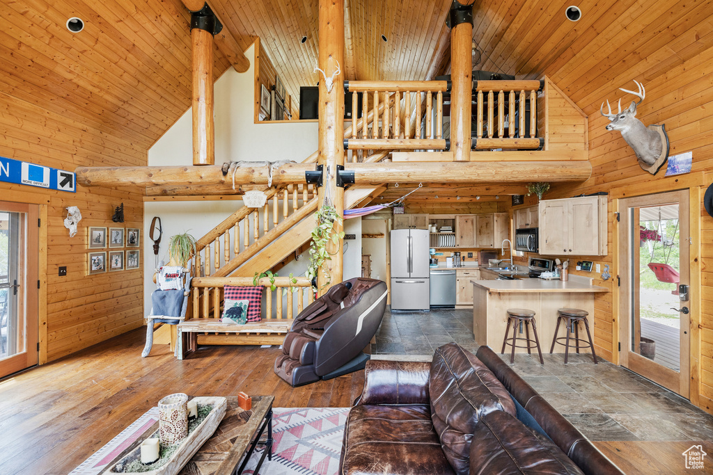 Living area featuring high vaulted ceiling, wood ceiling, wooden walls, and dark wood-style flooring