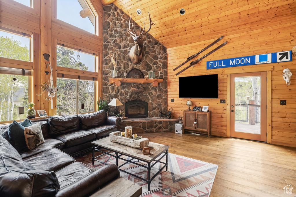Living area featuring high vaulted ceiling, hardwood / wood-style flooring, wooden ceiling, wooden walls, and a fireplace