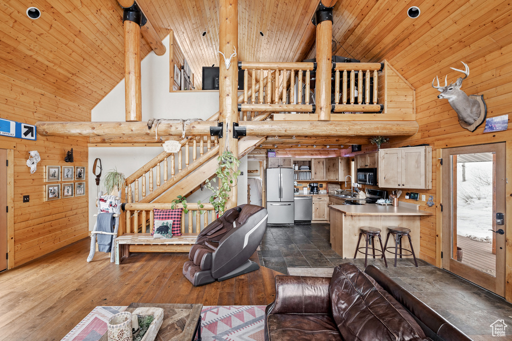 Living area featuring high vaulted ceiling, wood ceiling, wooden walls, and dark wood-style flooring