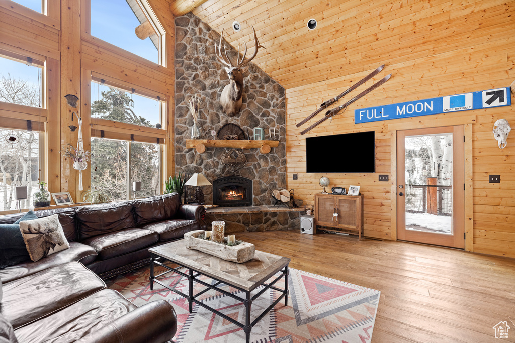 Living area featuring high vaulted ceiling, wood-type flooring, wooden ceiling, wood walls, and a fireplace