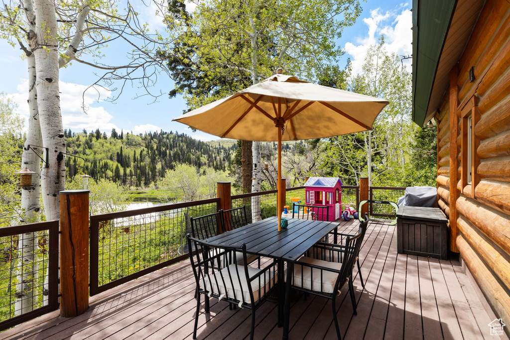 Wooden deck featuring outdoor dining area, a view of trees, and a water view