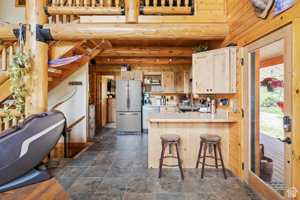 Kitchen with appliances with stainless steel finishes, stone tile floors, a peninsula, light countertops, and a breakfast bar area