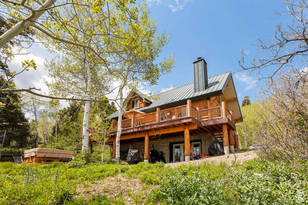 Rear view of property with metal roof, a deck, a standing seam roof, and a chimney
