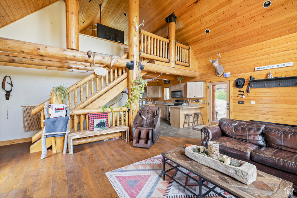 Living area with high vaulted ceiling, wood ceiling, hardwood / wood-style floors, and baseboards