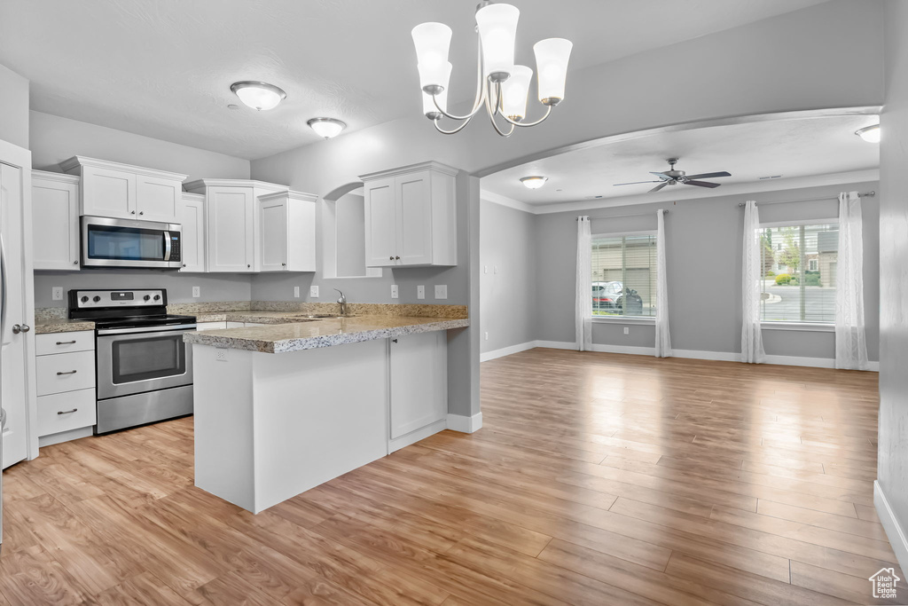 Kitchen featuring arched walkways, a peninsula, appliances with stainless steel finishes, and white cabinets