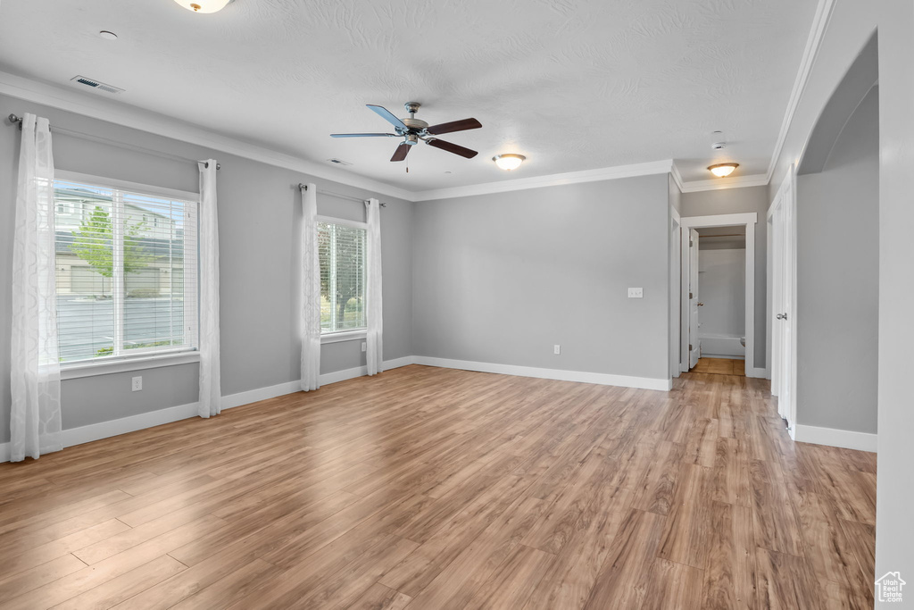 Unfurnished room featuring a wealth of natural light, visible vents, a ceiling fan, and arched walkways