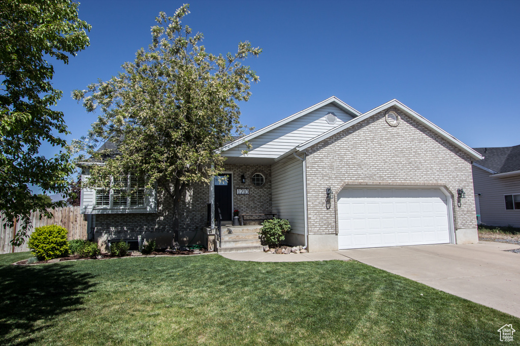 Ranch-style home with concrete driveway, a garage, brick siding, and a front yard