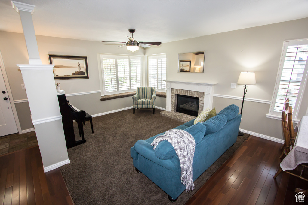 Living room with baseboards, a fireplace, a ceiling fan, and ornate columns