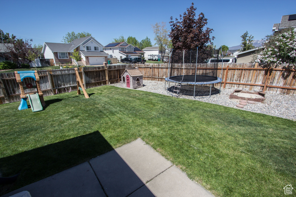 View of yard with a fenced backyard, a playground, a trampoline, and a residential view