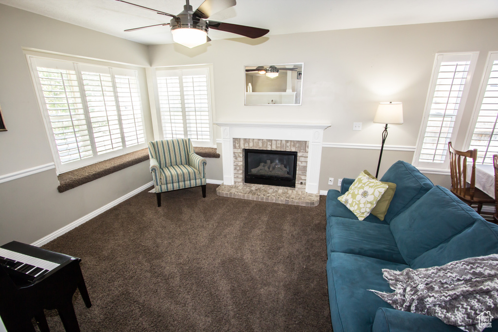 Carpeted living area featuring a fireplace, ceiling fan, and baseboards