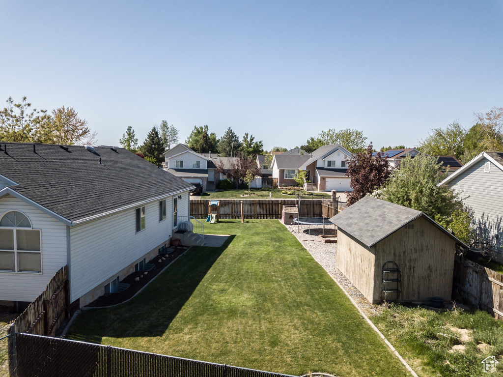 View of yard with a shed, an outdoor structure, a trampoline, a residential view, and a fenced backyard