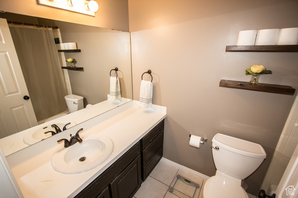 Full bath with toilet, baseboards, curtained shower, tile patterned flooring, and vanity