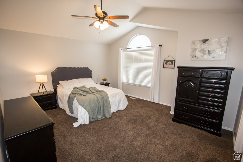 Bedroom with lofted ceiling, dark carpet, baseboards, and ceiling fan