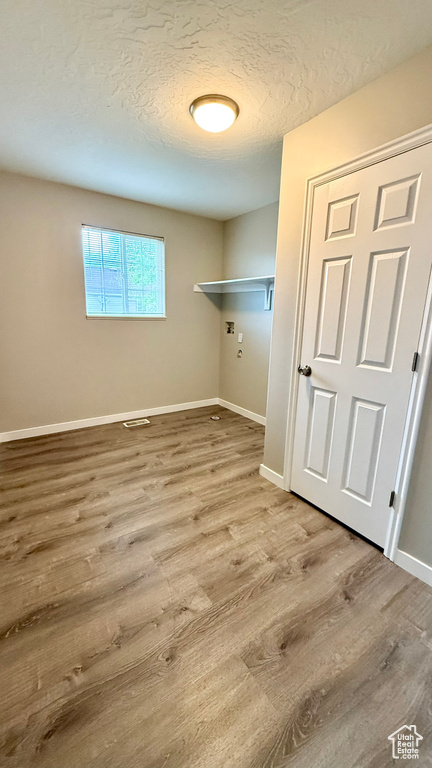 Washroom featuring wood finished floors, baseboards, a textured ceiling, and washer hookup