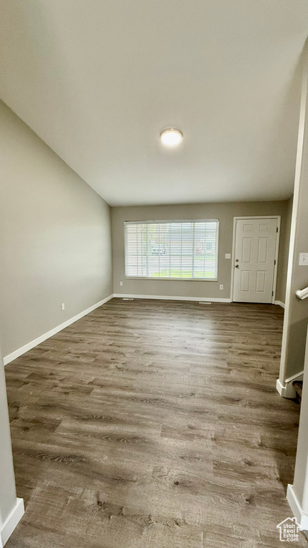 Unfurnished living room featuring baseboards and wood finished floors