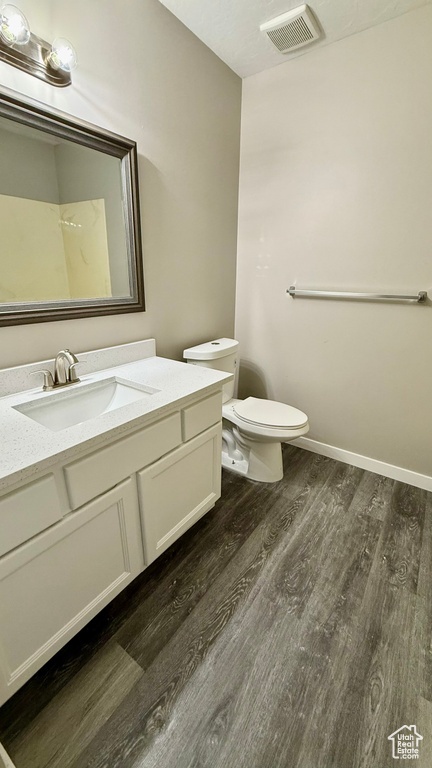 Bathroom featuring wood finished floors, toilet, vanity, and baseboards