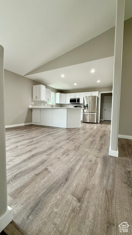 Unfurnished living room with baseboards, recessed lighting, light wood-type flooring, and vaulted ceiling
