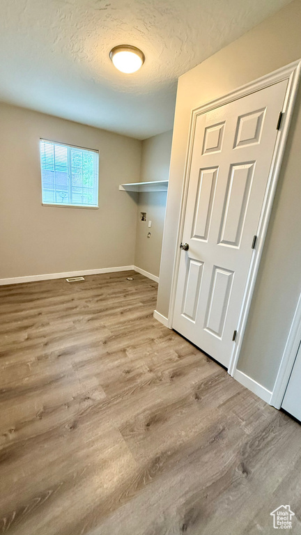Laundry area featuring wood finished floors, baseboards, a textured ceiling, and hookup for a washing machine