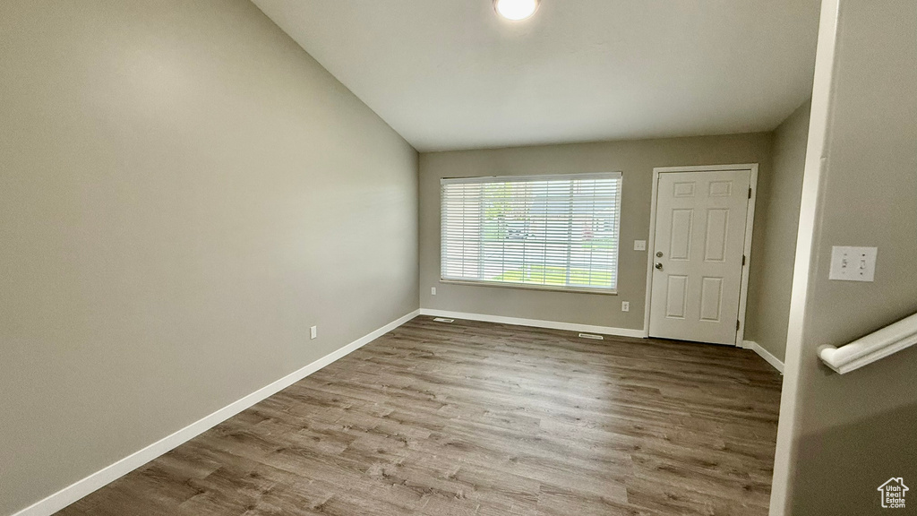 Spare room featuring vaulted ceiling, wood finished floors, and baseboards