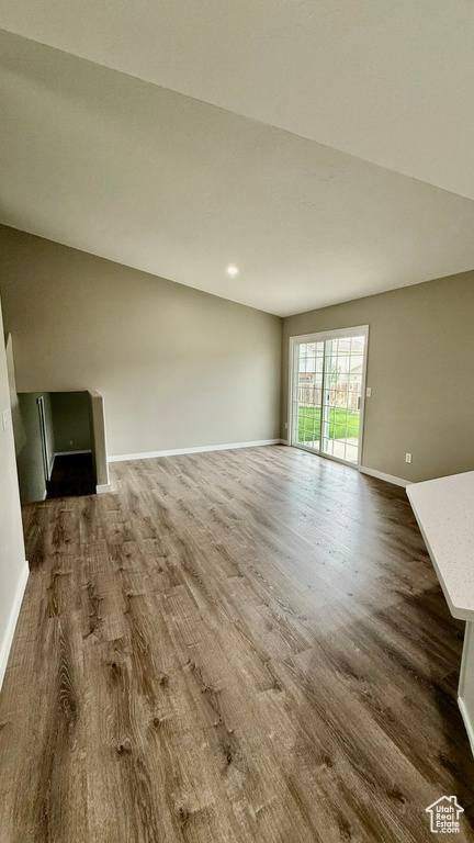 Unfurnished living room featuring dark wood-style floors and baseboards