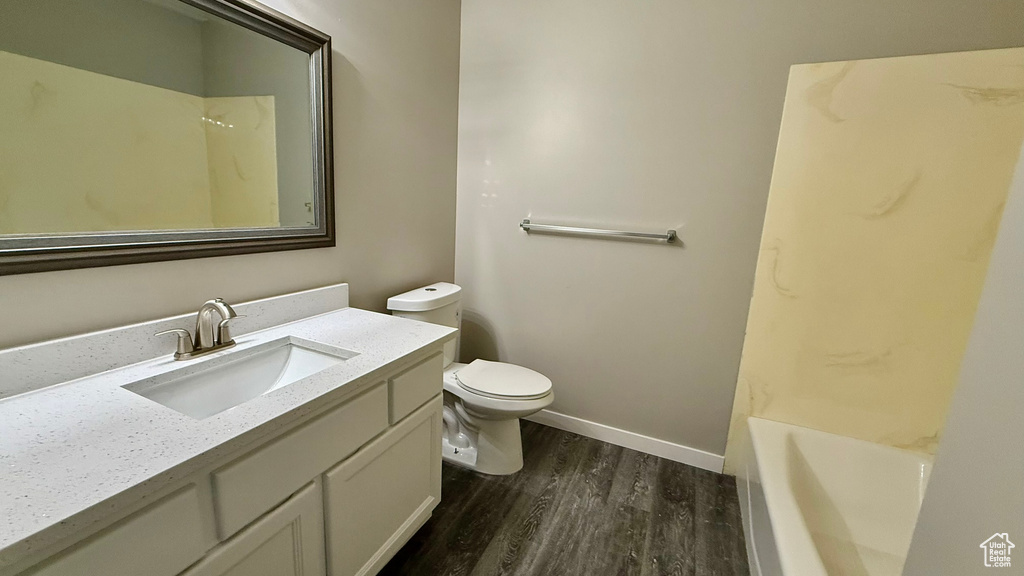 Full bathroom with wood finished floors, toilet, a tub to relax in, vanity, and a shower