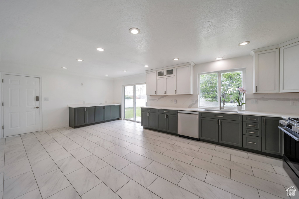 Kitchen with stainless steel appliances, a sink, light countertops, recessed lighting, and white cabinetry
