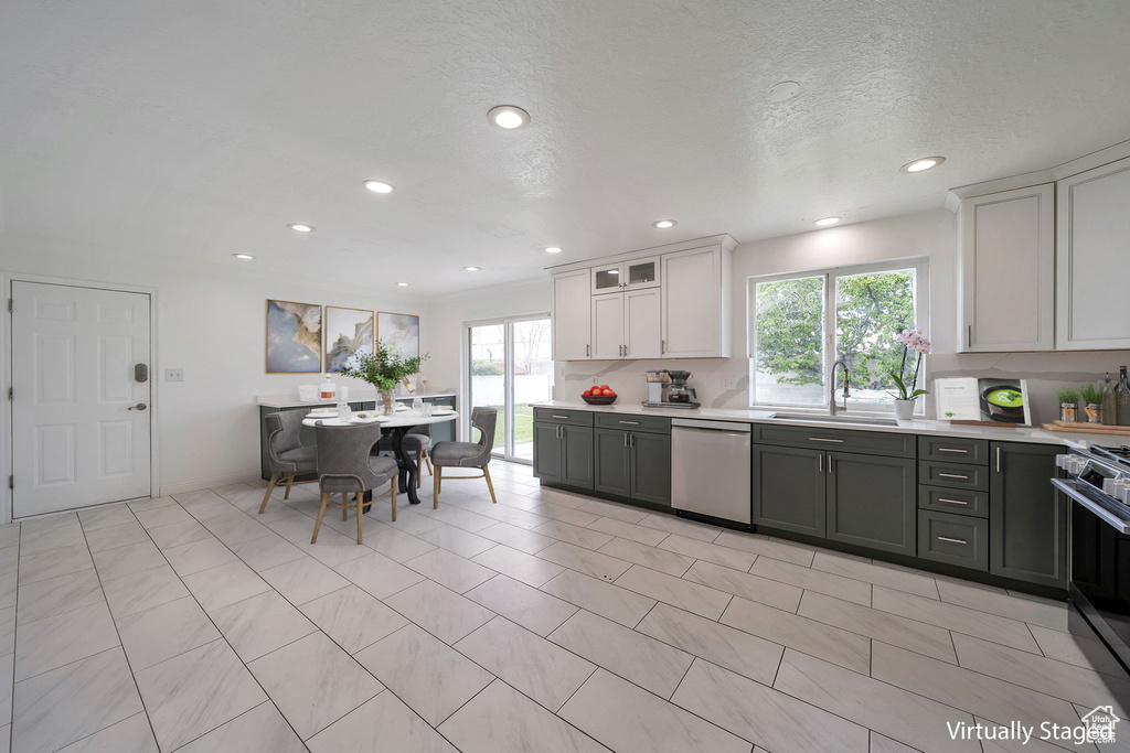 Kitchen with appliances with stainless steel finishes, light countertops, recessed lighting, white cabinetry, and glass insert cabinets