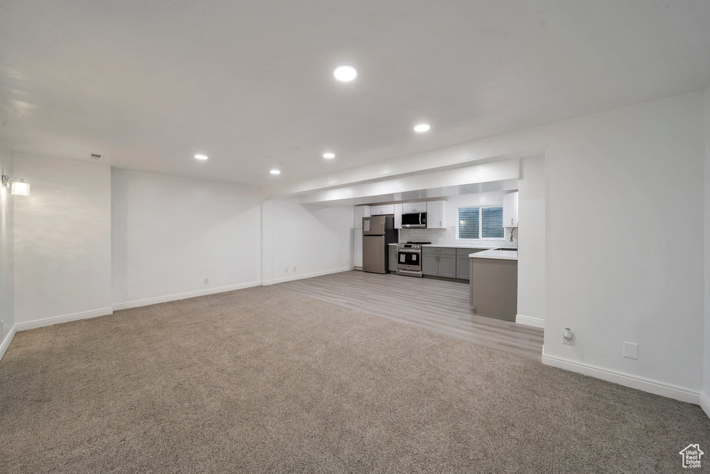 Unfurnished living room featuring light colored carpet, baseboards, and recessed lighting