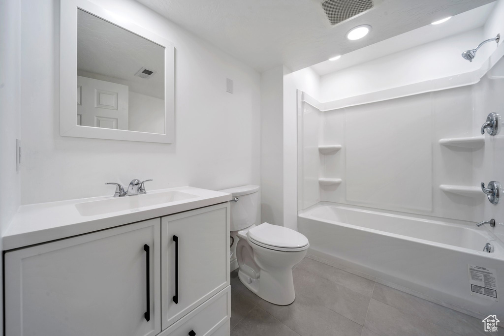 Full bathroom with tile patterned floors, toilet, vanity, and shower / bathtub combination