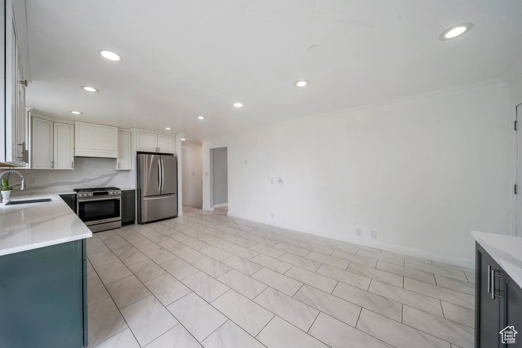 Kitchen with appliances with stainless steel finishes, a sink, recessed lighting, crown molding, and white cabinetry