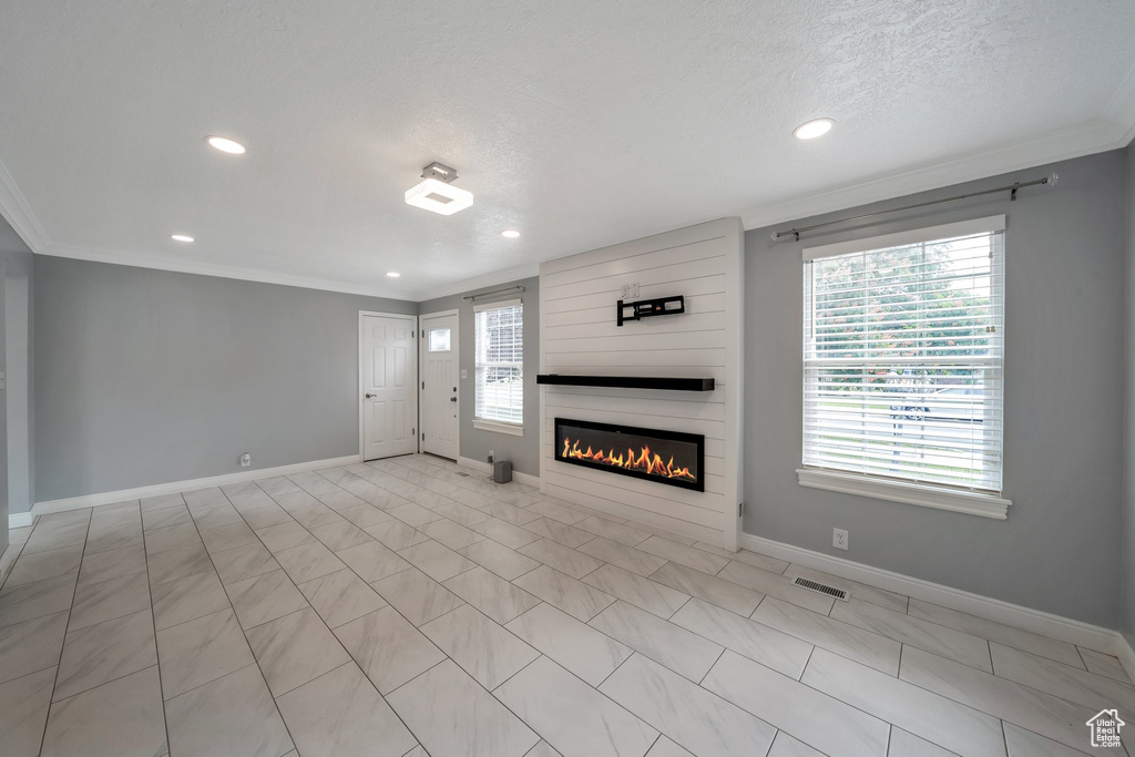 Unfurnished living room with crown molding, recessed lighting, baseboards, a large fireplace, and a textured ceiling