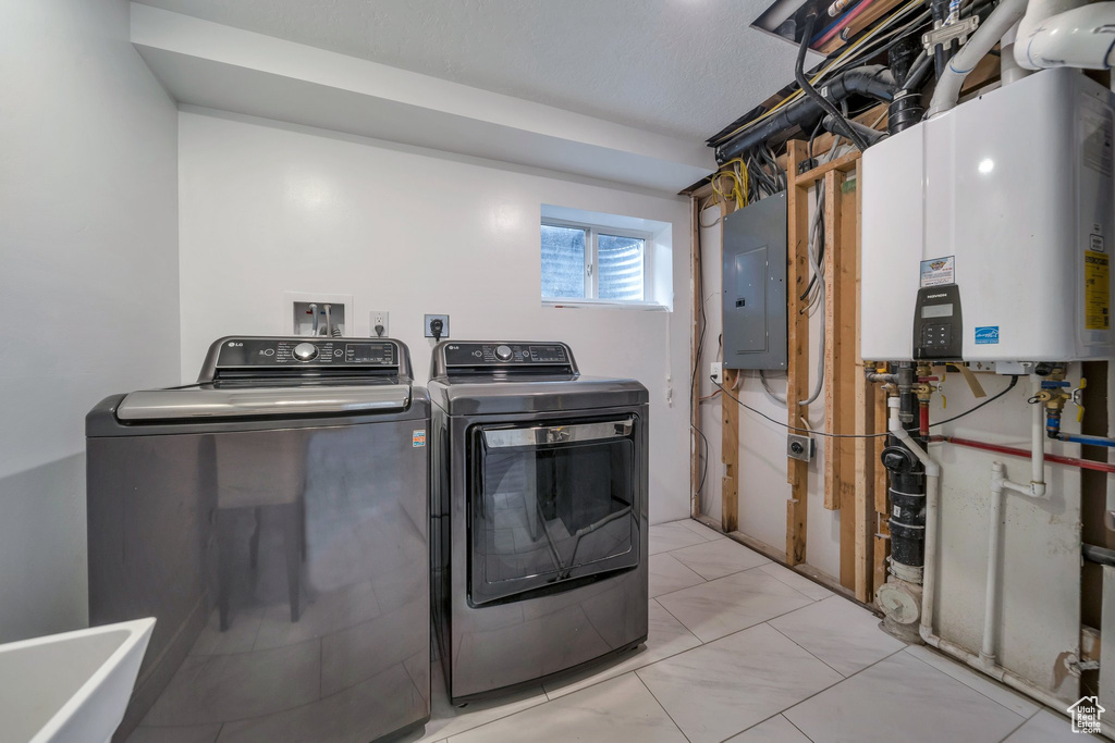 Laundry area featuring electric panel, washing machine and dryer, and water heater