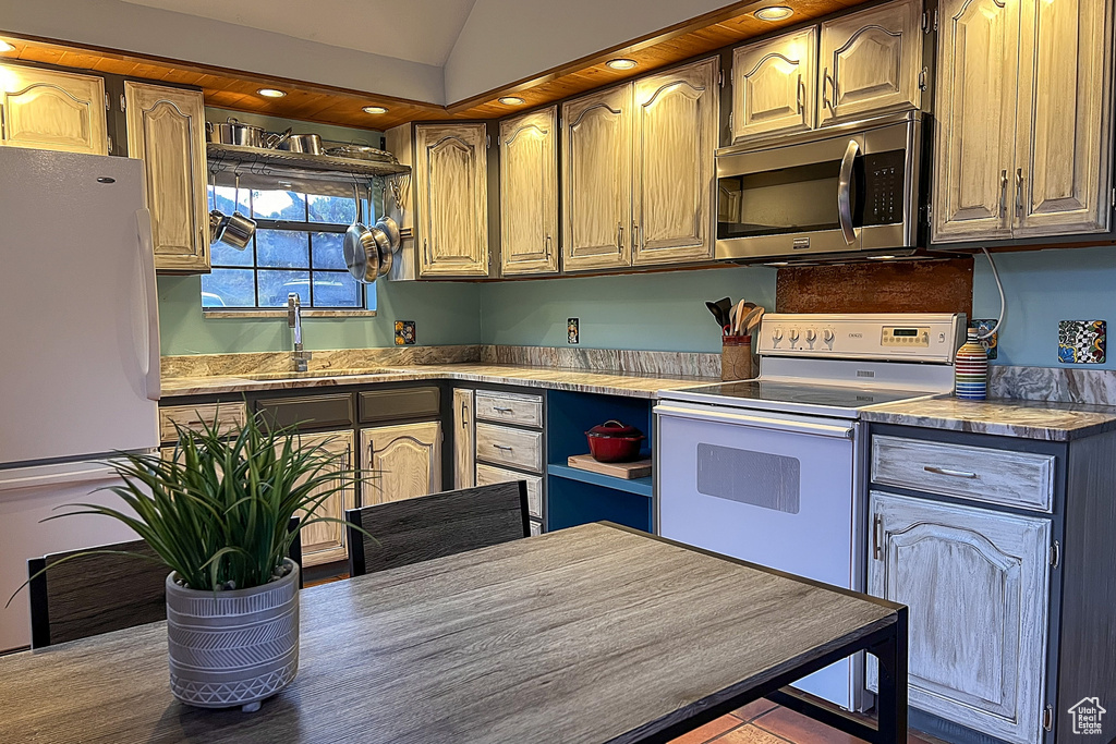 Kitchen with white appliances, recessed lighting, vaulted ceiling, and a sink