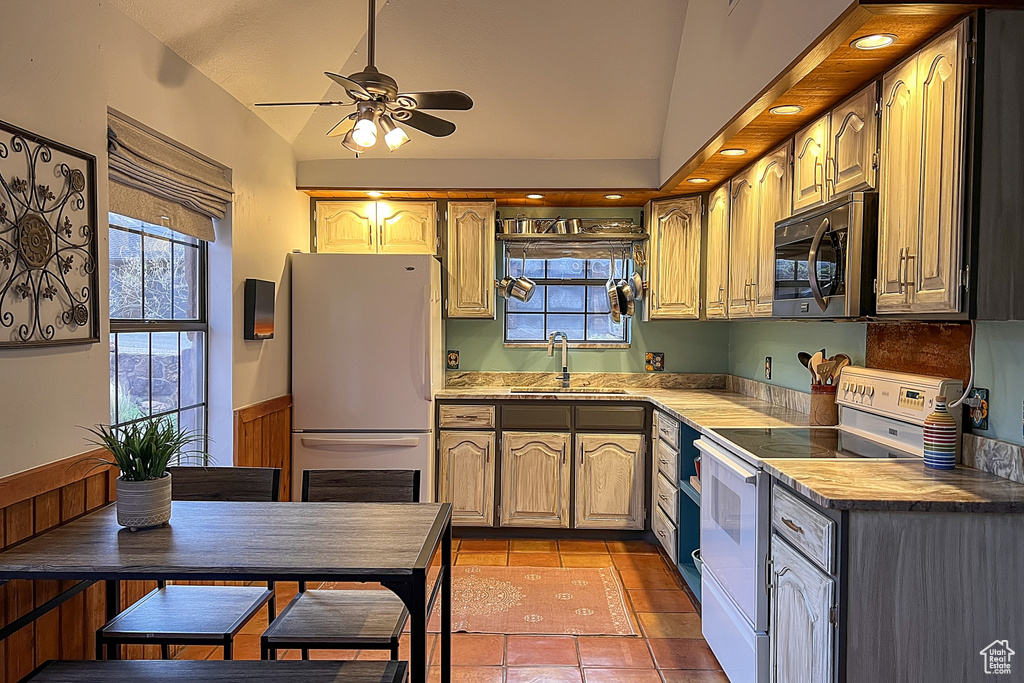 Kitchen with ceiling fan, a sink, white appliances, a wealth of natural light, and lofted ceiling