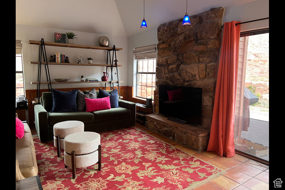 Tiled living area featuring lofted ceiling and a wainscoted wall