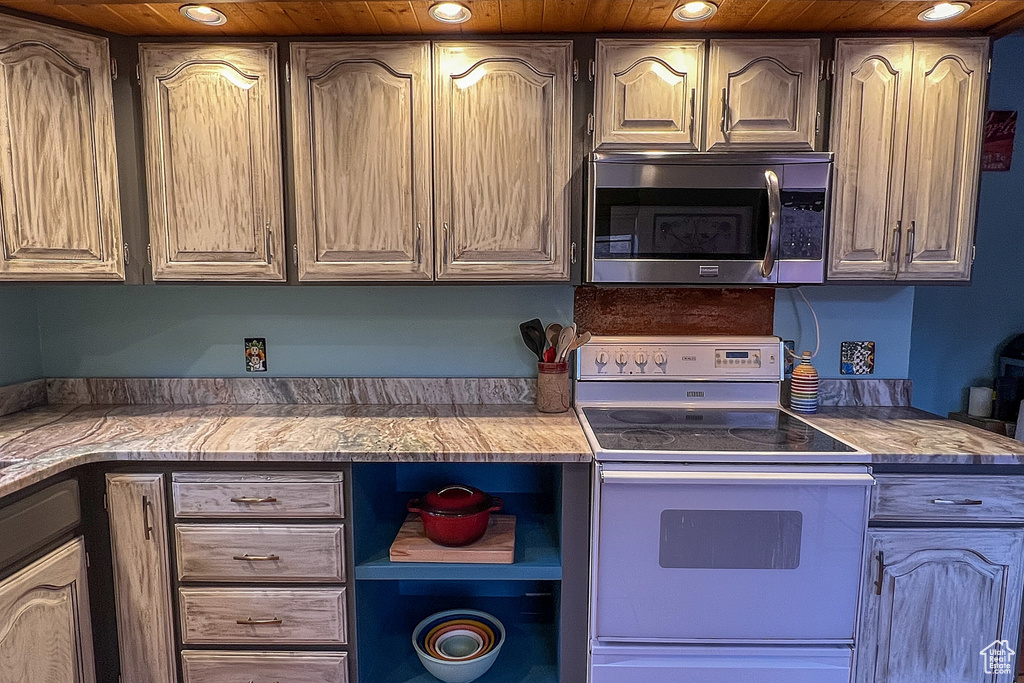 Kitchen with recessed lighting, light countertops, stainless steel microwave, and white range with electric cooktop