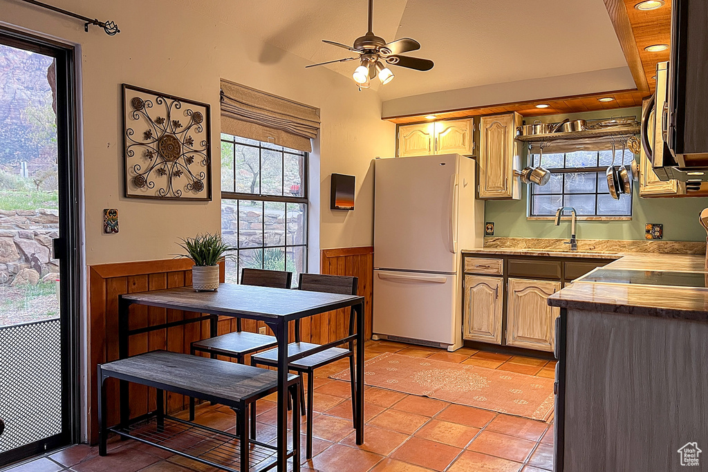 Kitchen featuring freestanding refrigerator, a sink, light tile patterned floors, and a wainscoted wall