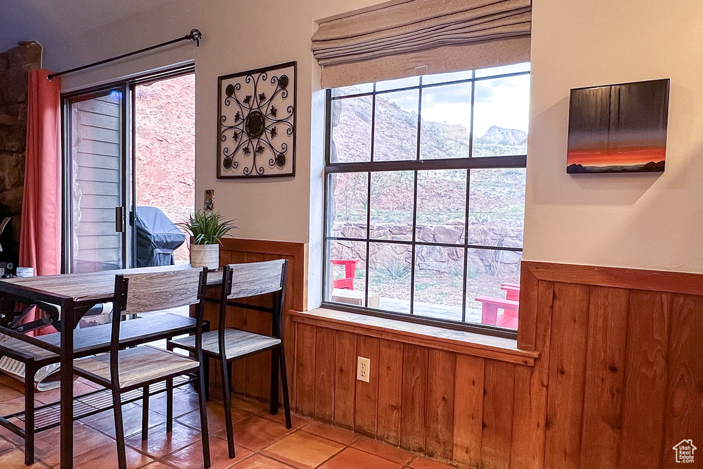Dining space with a mountain view, light tile patterned floors, a wainscoted wall, and wooden walls
