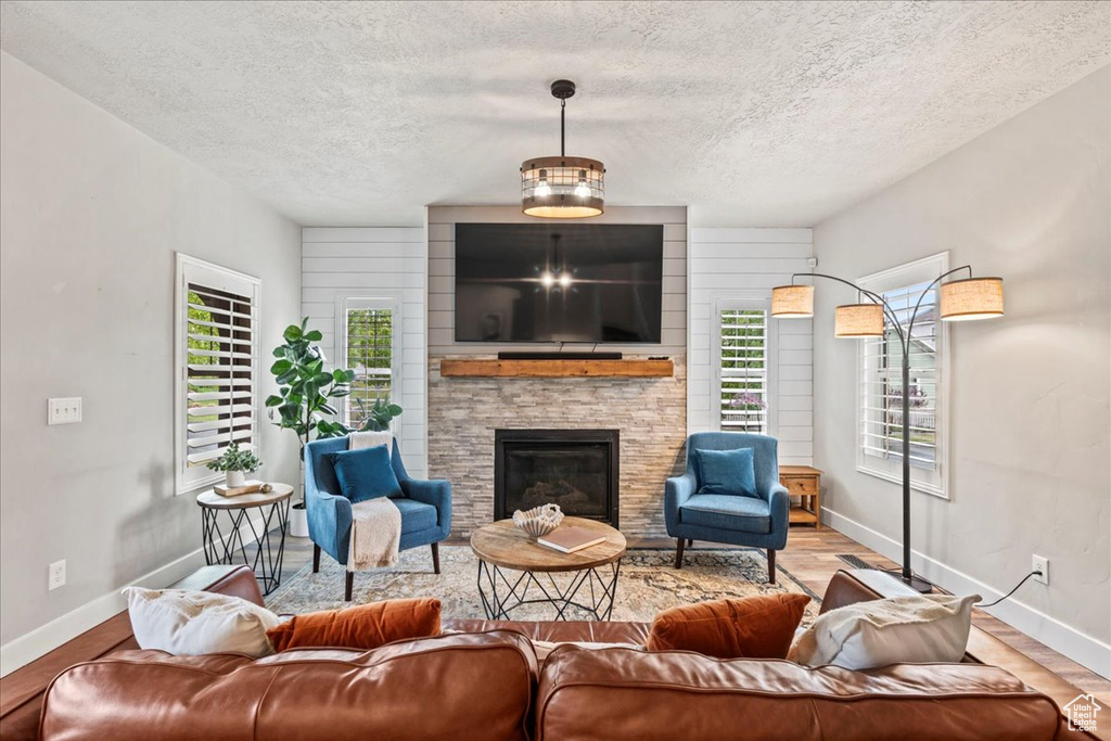 Living room with baseboards, a textured ceiling, wood finished floors, and a fireplace