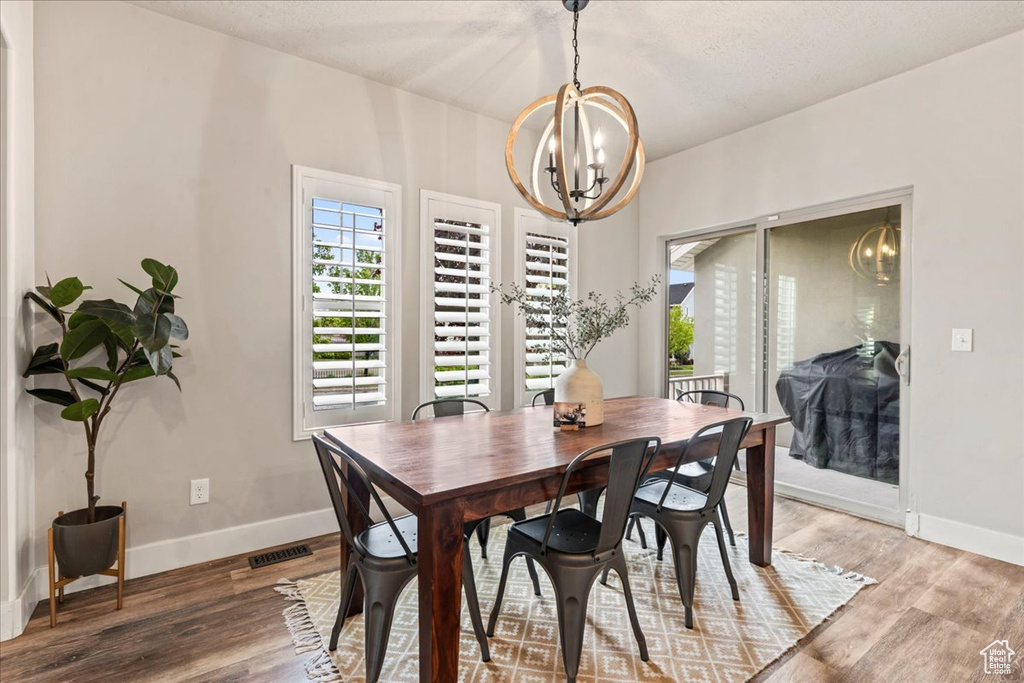 Dining room with baseboards, a chandelier, and light wood-style floors