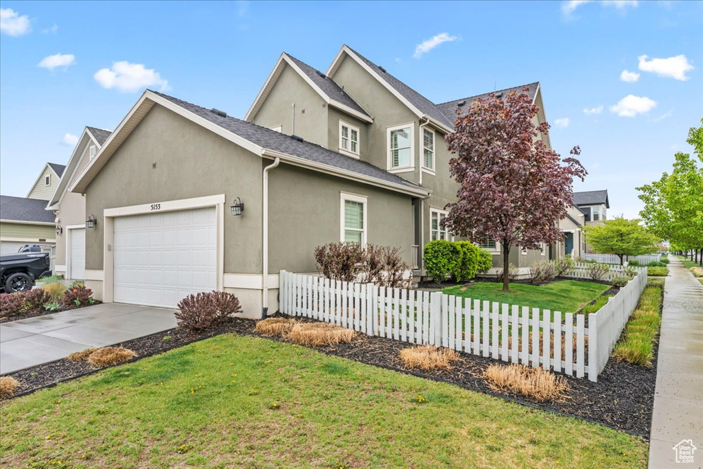 View of front of home featuring fence, stucco siding, driveway, and a garage