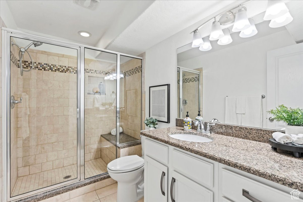 Bathroom featuring vanity, tile patterned floors, a stall shower, and toilet