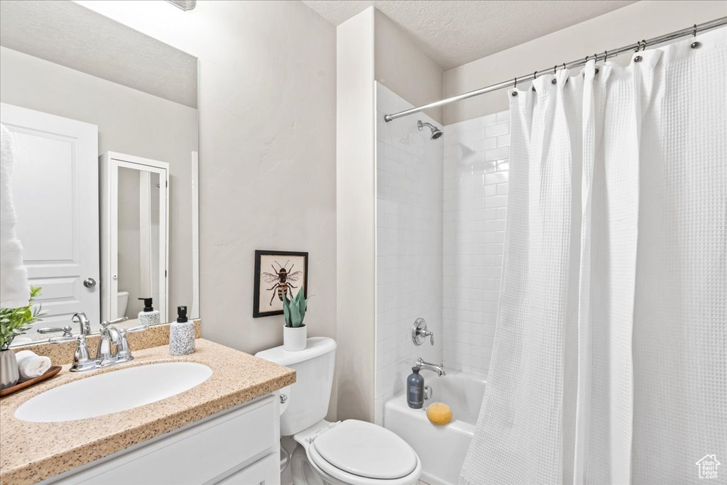 Full bath featuring toilet, shower / bathtub combination with curtain, and vanity