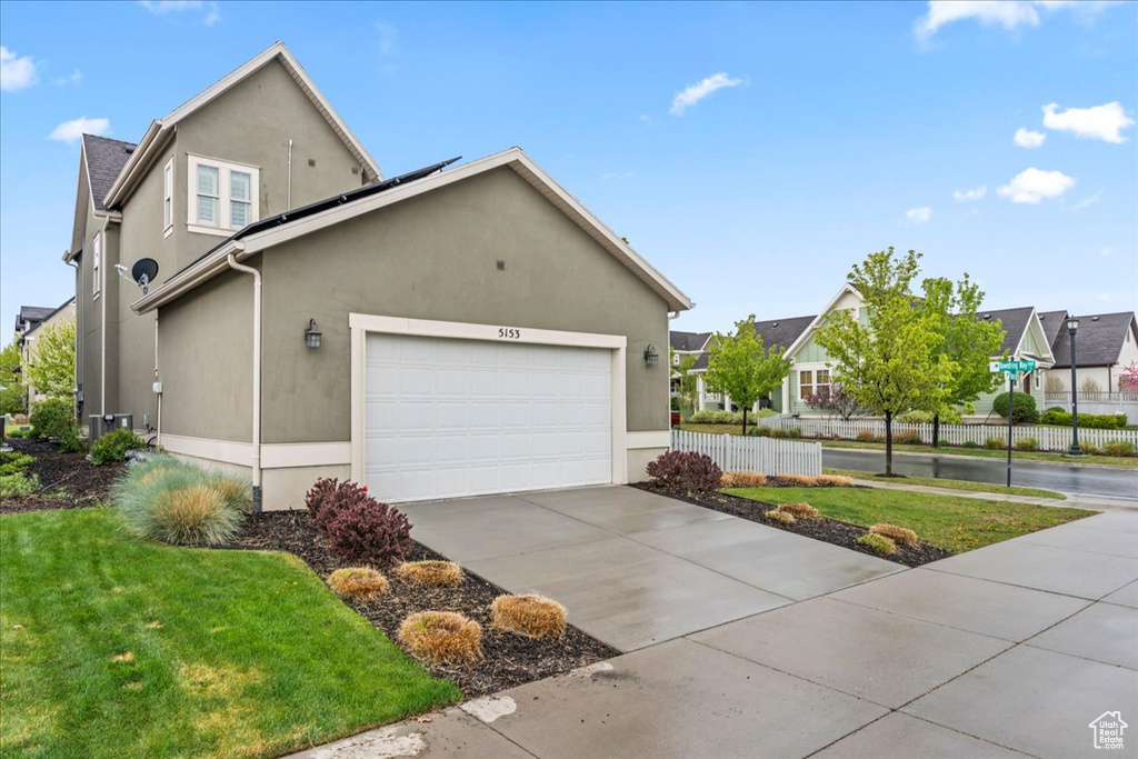 View of property exterior with stucco siding, fence, driveway, and solar panels