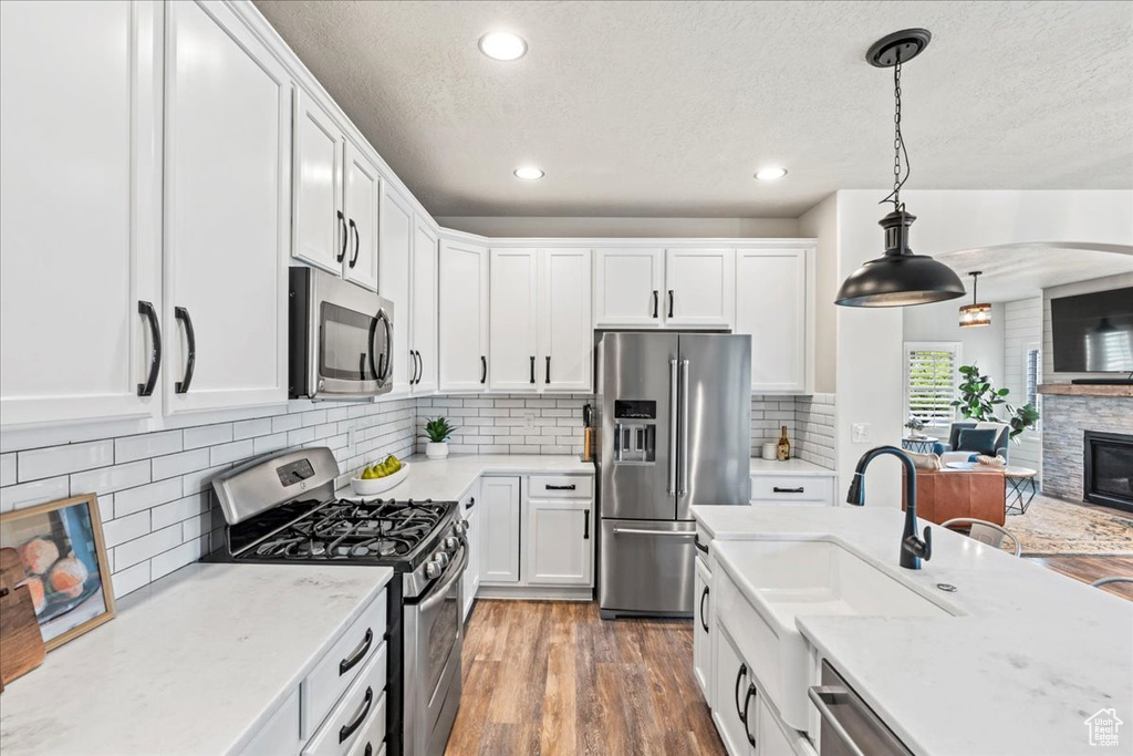 Kitchen with stainless steel appliances, a textured ceiling, and white cabinetry