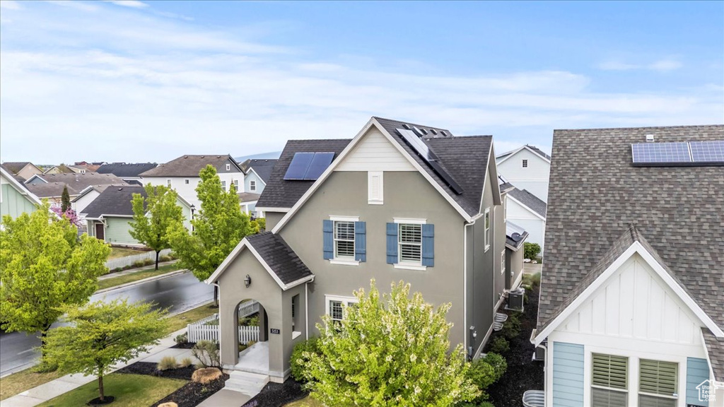 Traditional-style house with a shingled roof, board and batten siding, roof mounted solar panels, and a residential view